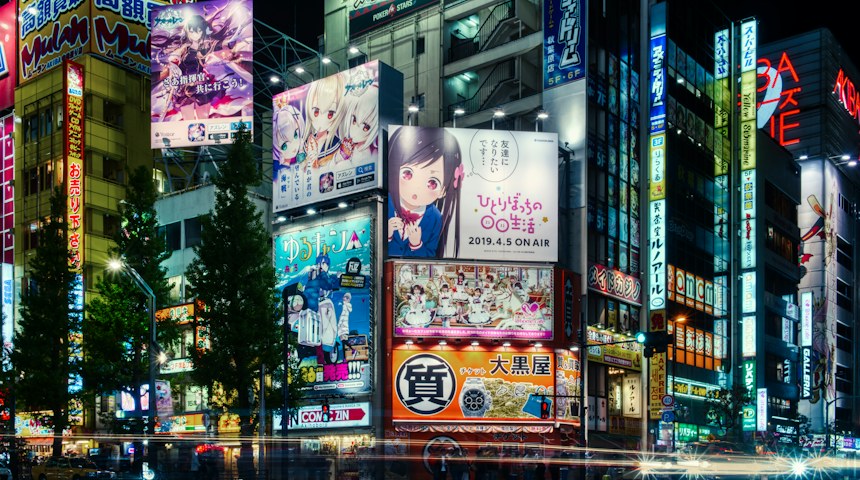 Illuminated anime billboards on buildings in Akihabara at night