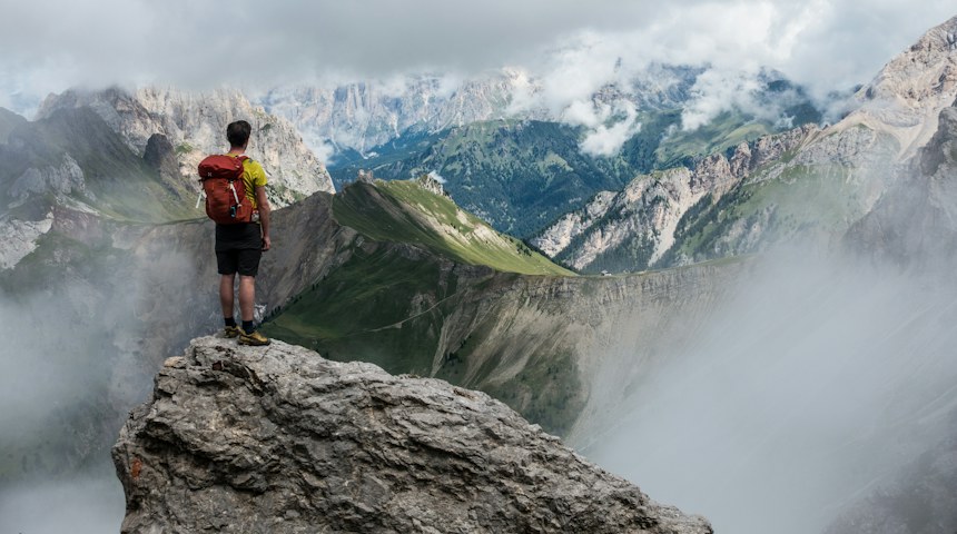 Hiker with a red backpack looking out over the mountains