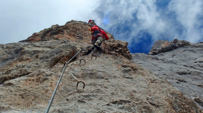 Climber ascending a rock face on a mountain route