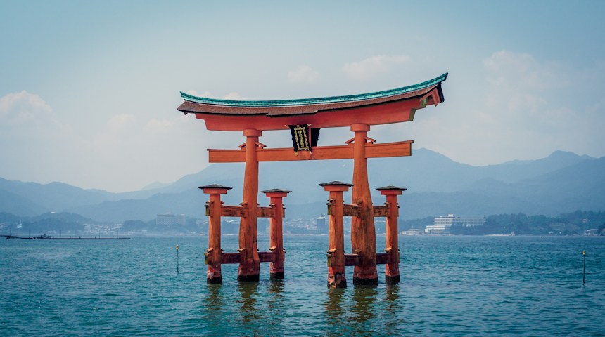 Orange Itsukushima Shrine torii gate standing in the sea at Miyajima