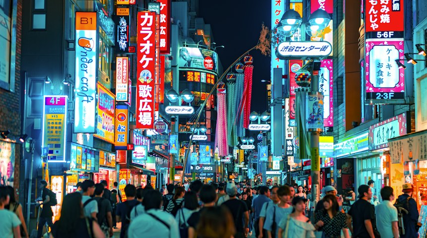 Crowds crossing the neon-lit Shibuya scramble crossing in Tokyo at night