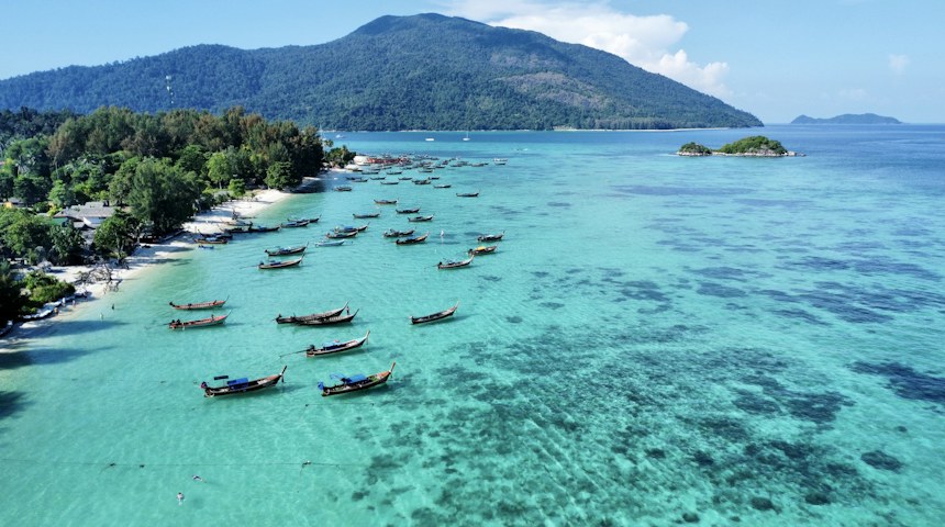 Boats floating in a clear bay at Koh Phi Phi