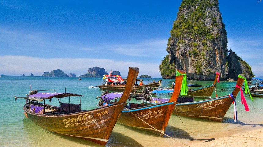 Wooden longtail boats lined up on a beach in southern Thailand