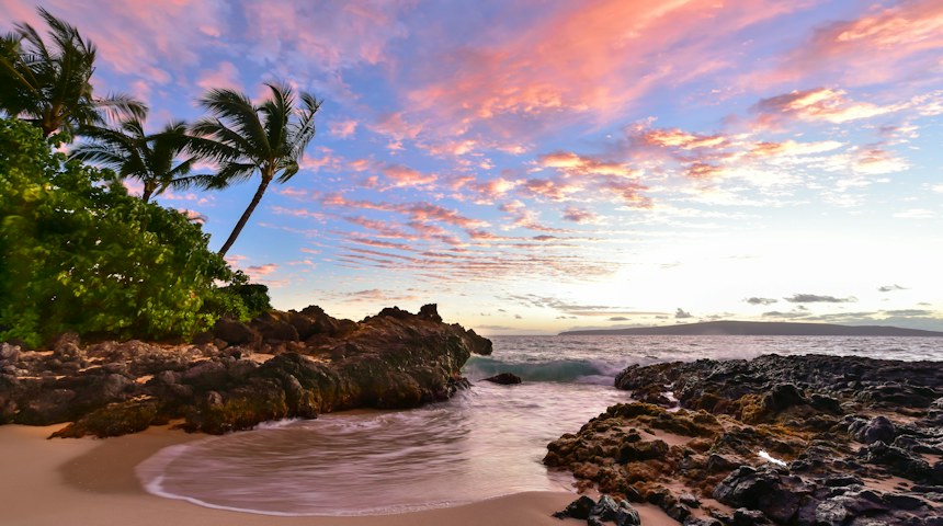 Beach with dark rocks and blue water on Maui