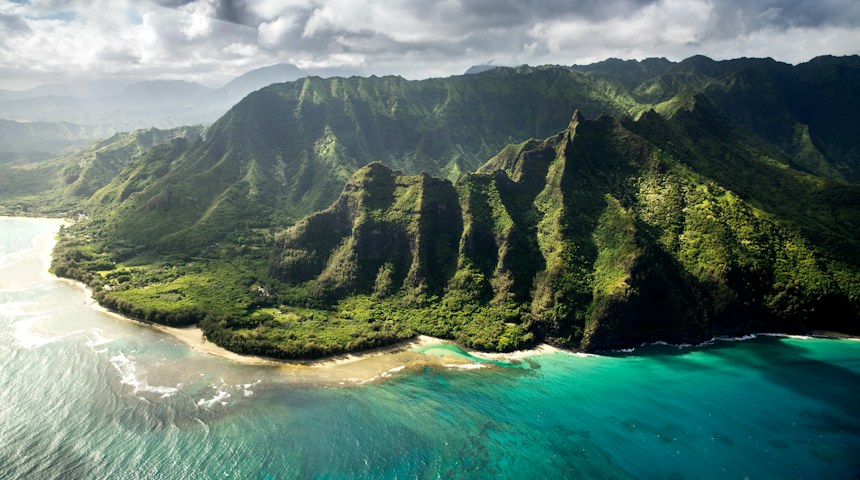 Aerial view of lush green cliffs and coastline in Hawaii