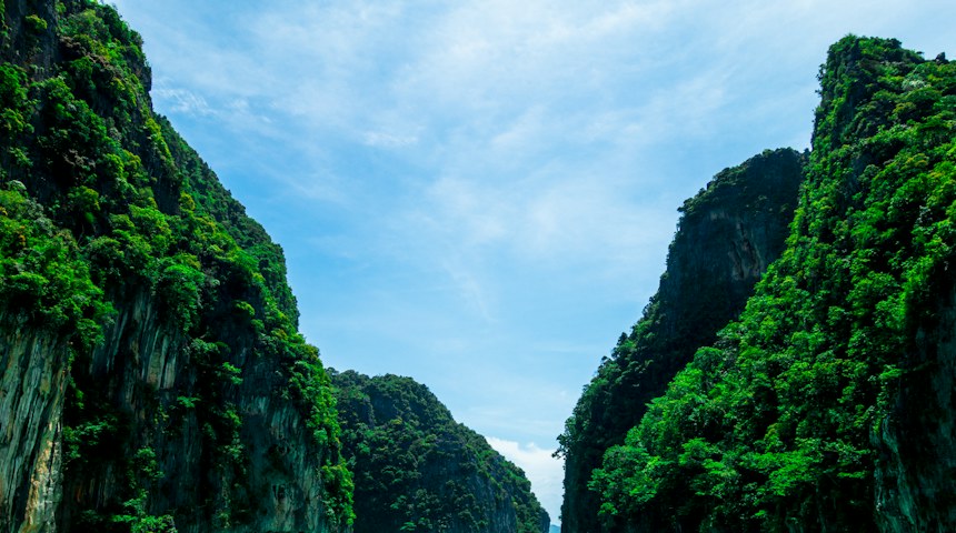 Boats anchored in a bay near green mountains in Phuket