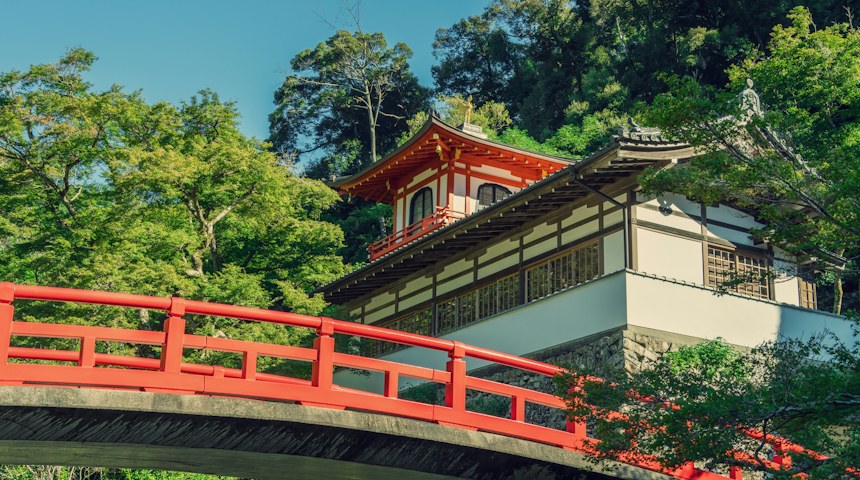 Red bridge crossing a river in a Japanese forest