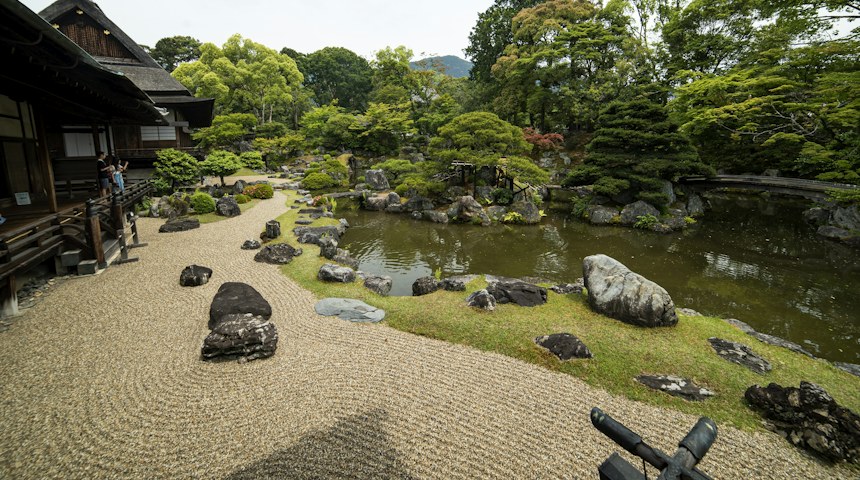 Wooden Japanese houses beside a garden pond with rocks