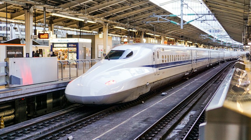 White Shinkansen bullet train arriving at a station platform in Japan