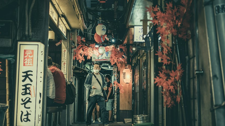 Diners sitting at the counter of a busy Japanese izakaya