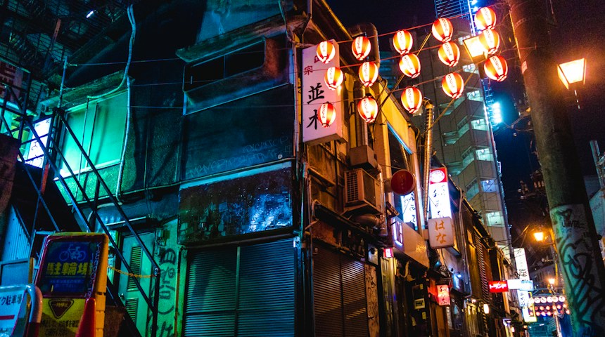 Red paper lanterns hanging over a narrow Japanese alley at night