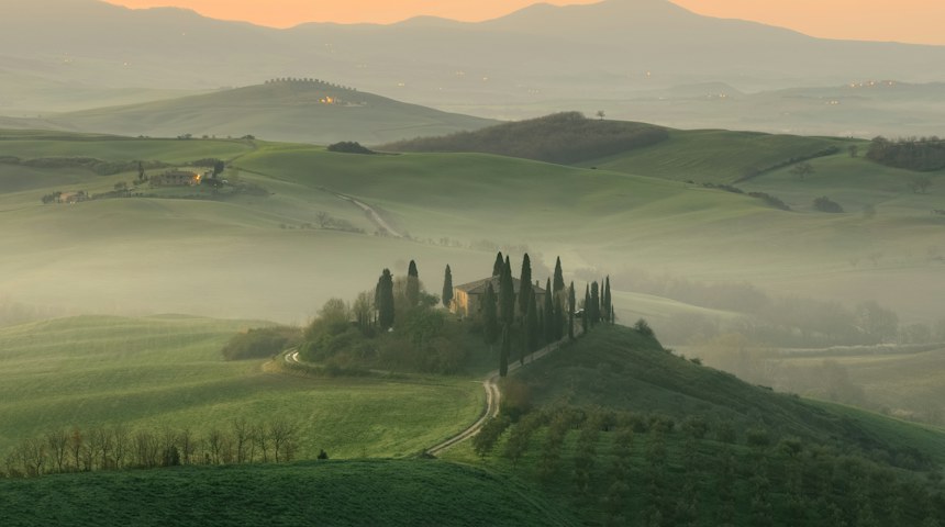 Farmhouse in the middle of green fields in the Tuscan countryside